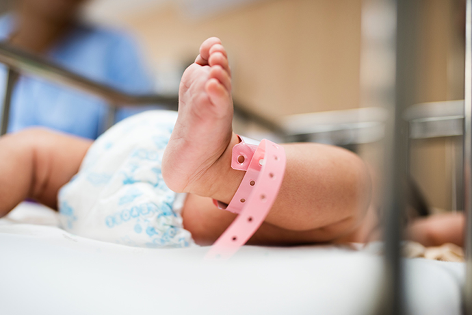 Baby wearing pink ankle bracelet strap